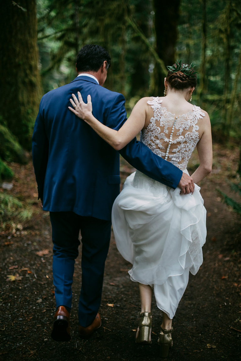 Father of the bride and the bride walking through the woods