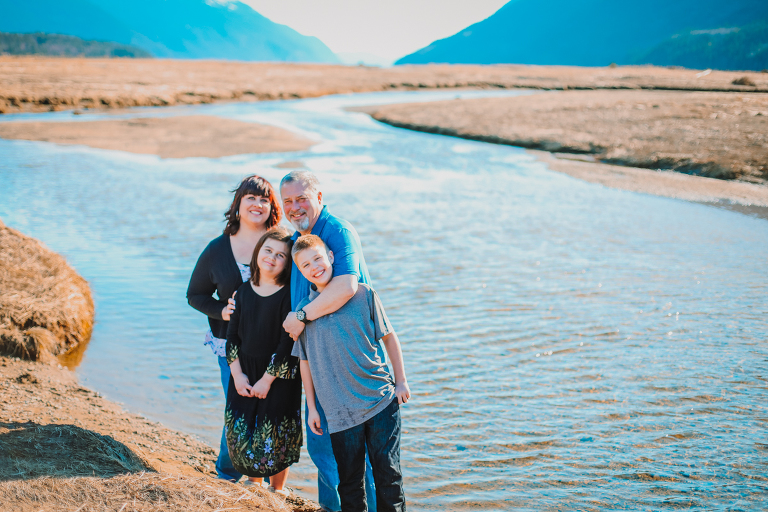 The Calver family smiles alongside a river on the Dyea Flats. 