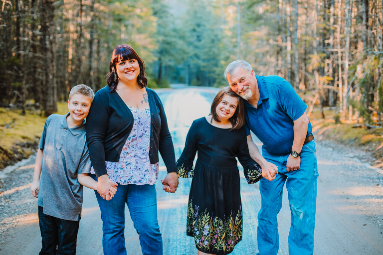 The Calver family holds hands and smiles, looking directly into the camera. 