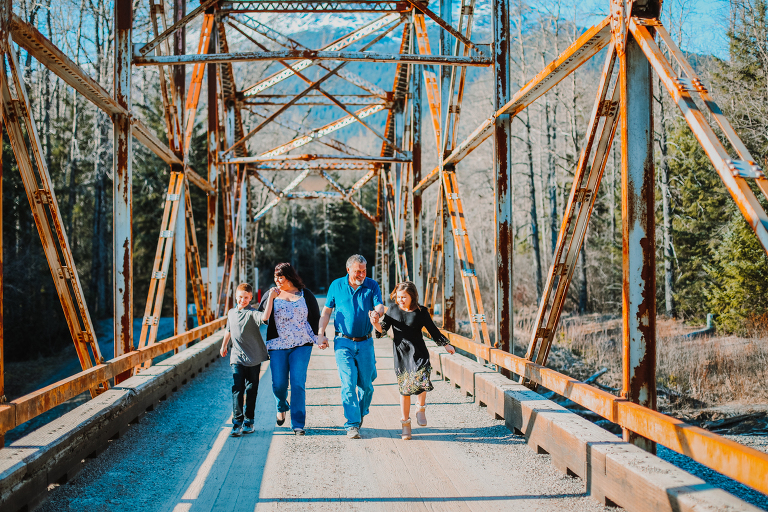 The Calver family walks hand in hand laughing down the Dyea Bridge. 
