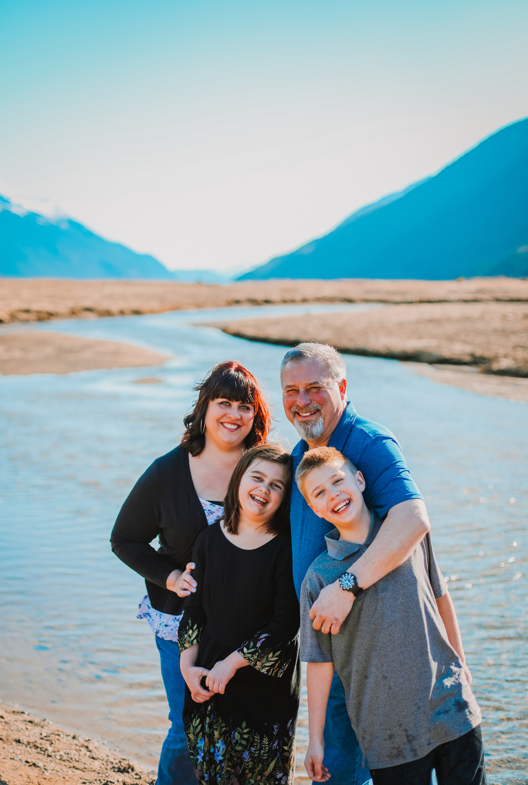 The Calver family smiles alongside a river on the Dyea Flats. 