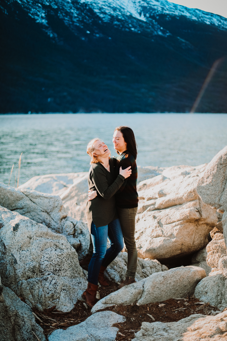 A young woman helping her girlfriend off a pile of rocks at Yakutania Point in Skagway, Alaska. 