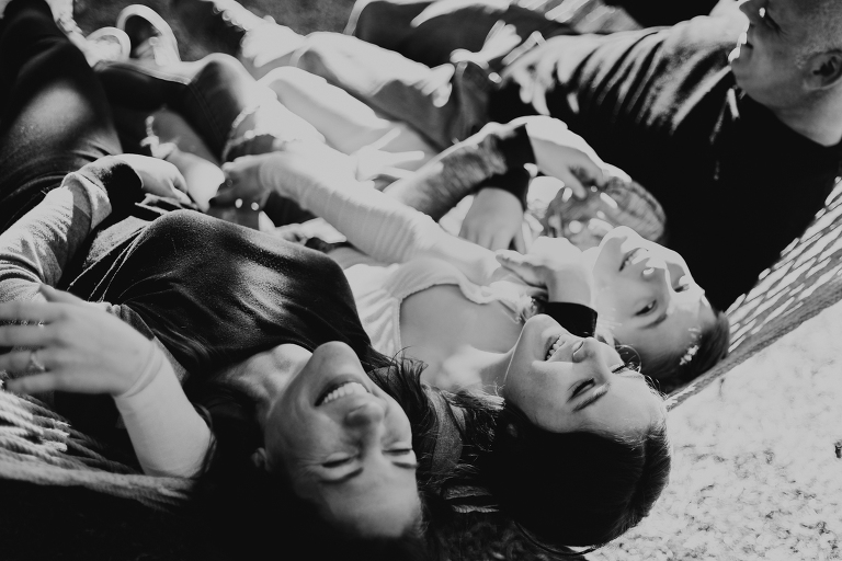 A black and white photo of the family laughing together while lying in a hammock. 