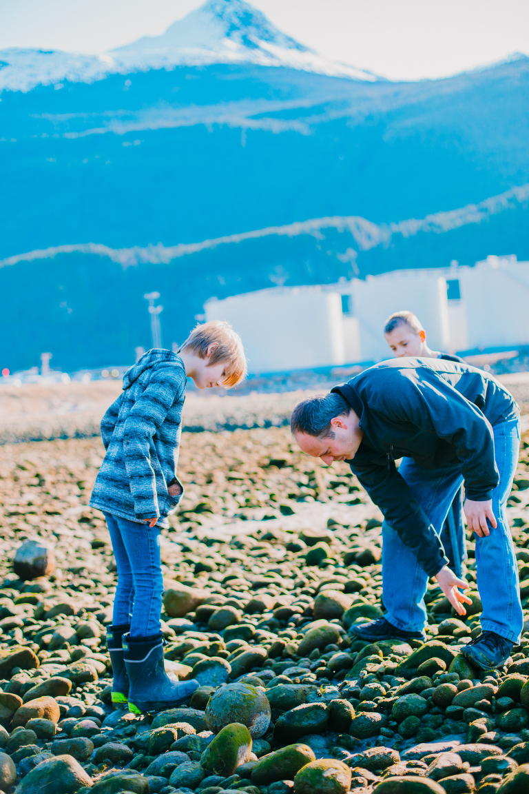 A father looks for rocks to throw with his twin boys. 