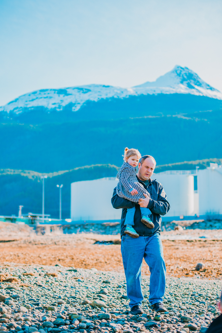A father carries his daughter through a grassy field in Skagway. 