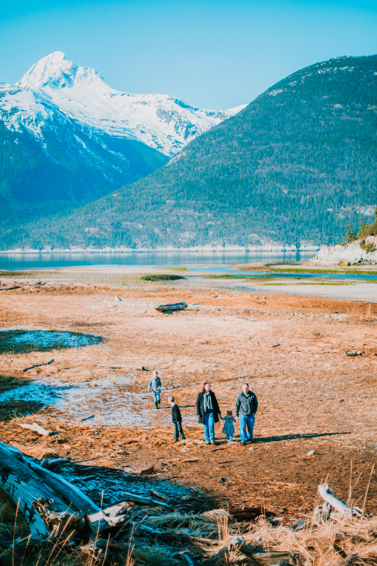 A family walks hand in hand on a grassy flats in Skagway. 