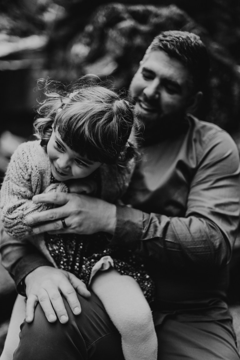 A black and white photo of dad tickling his daughter. 