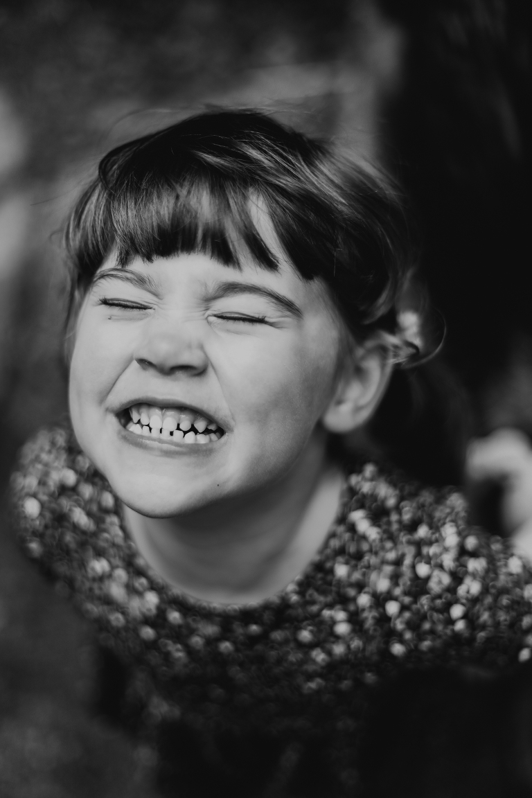 Little girl gives a huge smile with her eyes closed. 