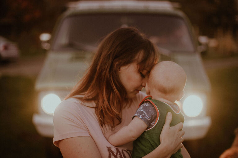 Mama holds her baby in front of a 1973 Dodge Tradesman. 