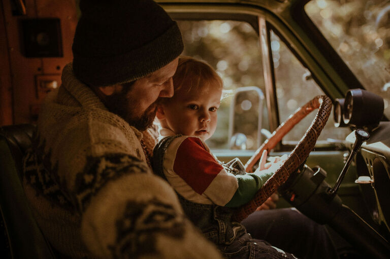 Dad and son sit in a seventies van. 