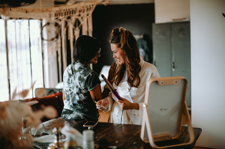 Kristi laughs with her best friend while doing her hair the morning of her elopement.