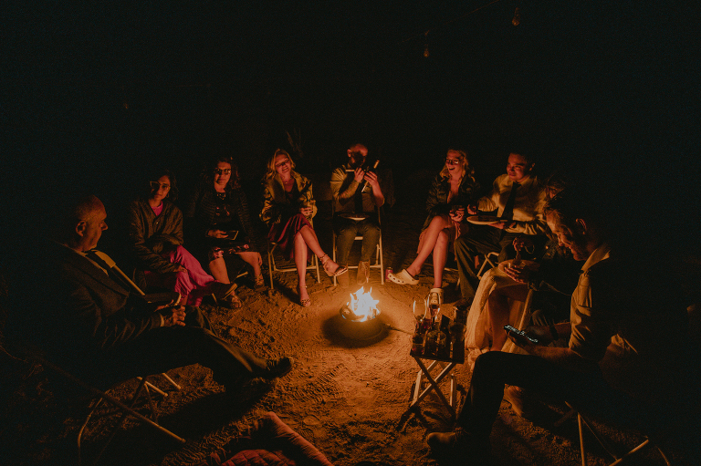 The wedding party sits around the campfire underneath the stars in Alabama Hills.